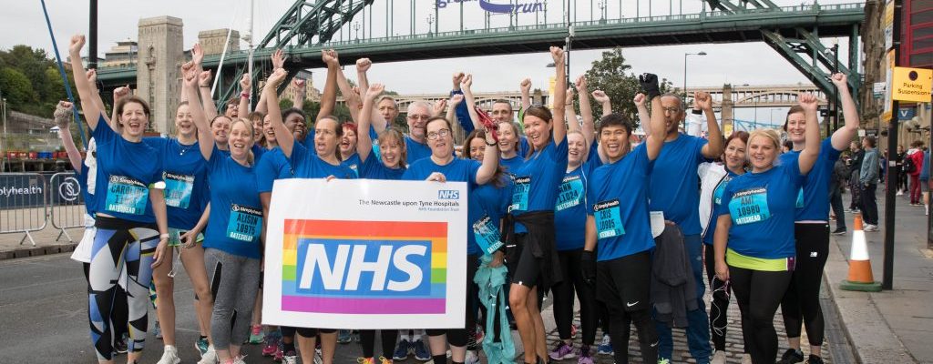 Group of people stood under the Tyne Bridge after completing the Great North Run.