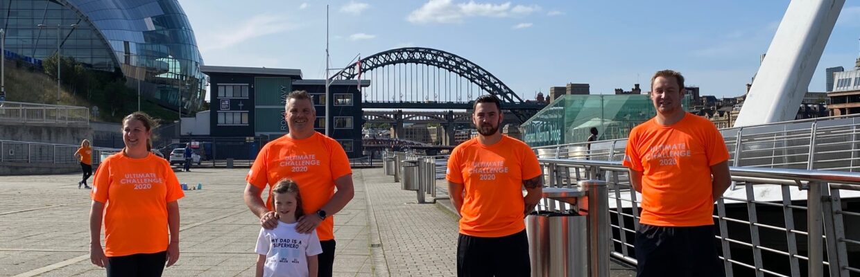 People stood smiling with the Tyne bridge behind.